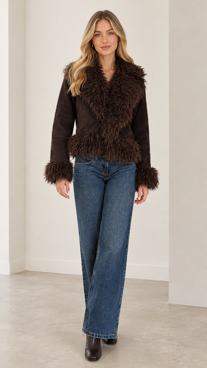 Full front view of a woman wearing the brown faux suede jacket with shaggy trim and blue jeans