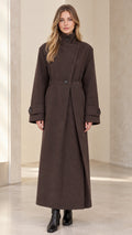 Front full-length view of model wearing brown asymmetric high-neck belted maxi overcoat