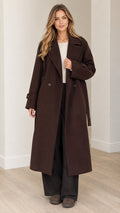 Front view of woman wearing brown longline belted overcoat with notch lapels