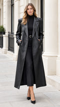 Front full-length view of woman wearing long black faux leather maxi trench coat with notched lapels