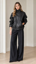 Front view of model wearing black faux leather bomber jacket and matching wide-leg pants