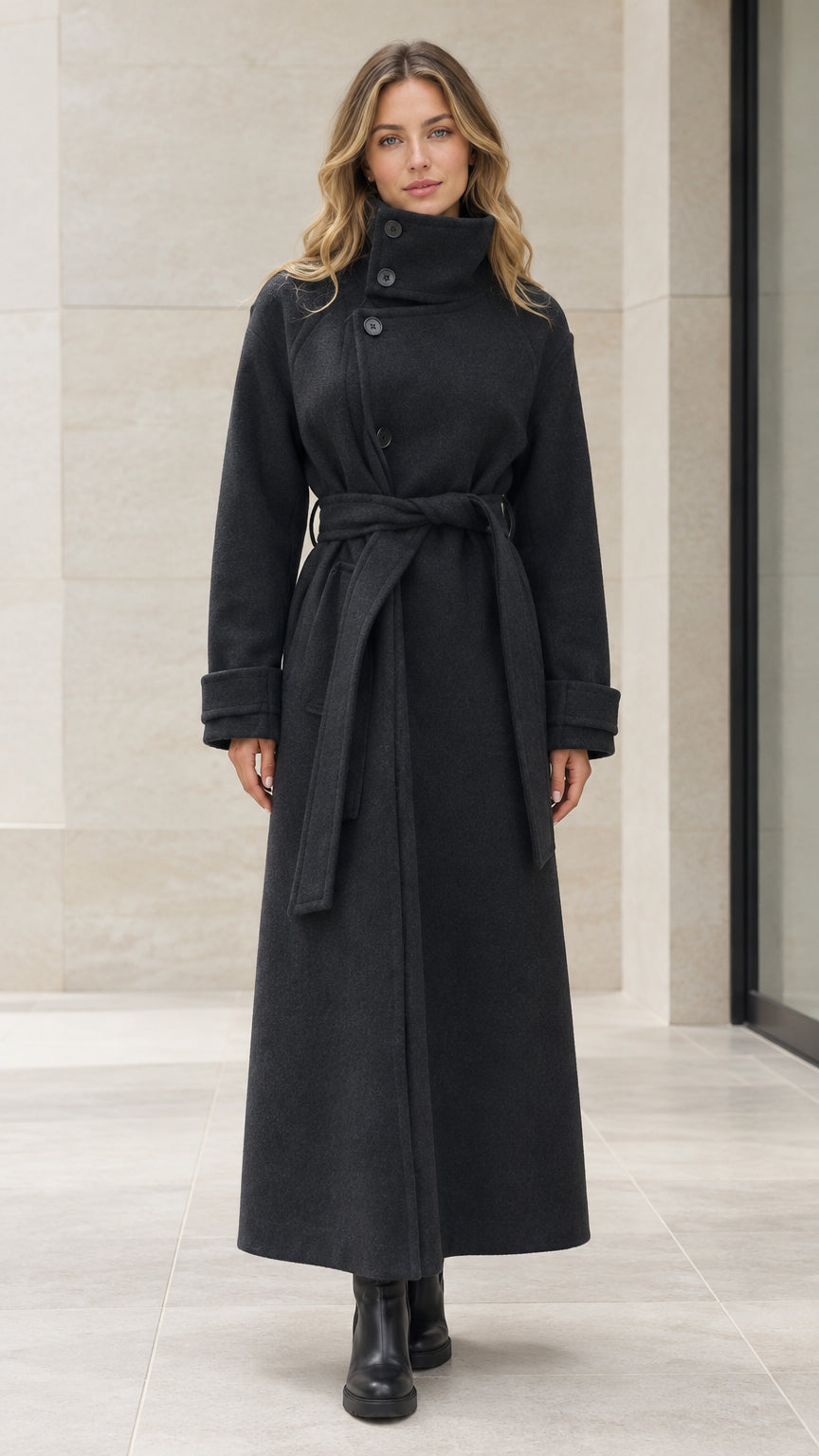 Front view of woman wearing full length black maxi overcoat with high neck and belted waist