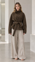 Front full view of woman wearing dark olive belted high-neck suede jacket with wide leg trousers