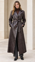Front view of model wearing dark brown faux leather maxi trench coat belted at waist