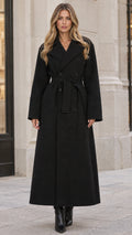 Front view of woman wearing a black double-breasted maxi coat with tied belt