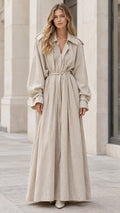 Full front view of model wearing a beige long sleeve trench-style maxi dress with tie belt