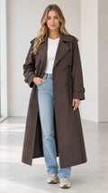 Front full view of woman wearing a long dark brown double-breasted trench coat open over white tee and blue jeans