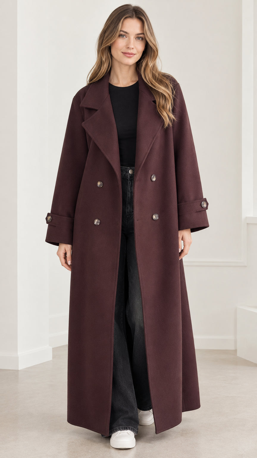 Front view of model wearing a burgundy double-breasted maxi overcoat with notch lapels