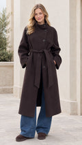 Front full view of woman wearing a dark brown asymmetrical high-neck belted longline overcoat