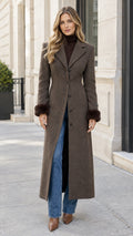 Front view of woman wearing brown tailored maxi coat with fur-trim cuffs