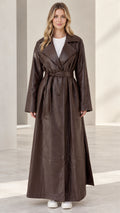 Front full-length view of woman wearing brown maxi faux leather belted trench coat
