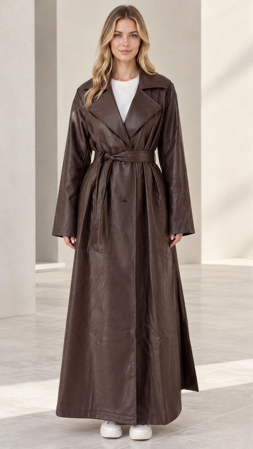 Front full-length view of woman wearing brown maxi faux leather belted trench coat