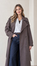 Front view of woman wearing full-length charcoal double-breasted trench coat with dark jeans