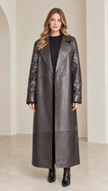 Front full view of woman wearing dark brown maxi faux leather trench coat with wide lapels