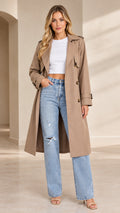 Full front view of model wearing khaki long double-breasted trench coat with jeans
