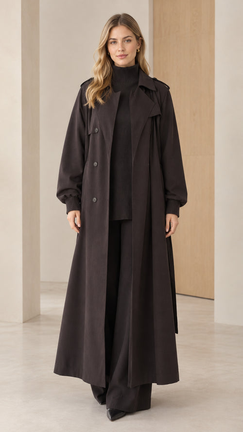 Front full-length view of woman wearing black maxi trench coat over matching outfit