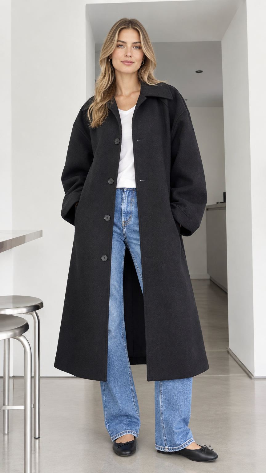 Front full-length view of model wearing black oversized maxi overcoat with turn-down collar