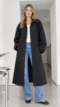 Front full-length view of model wearing black oversized maxi overcoat with turn-down collar