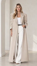 Front view of woman wearing beige floor-length maxi overcoat with white trousers
