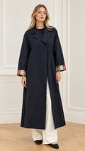 Front full-length view of woman wearing navy blue maxi trench coat with plaid cuffs
