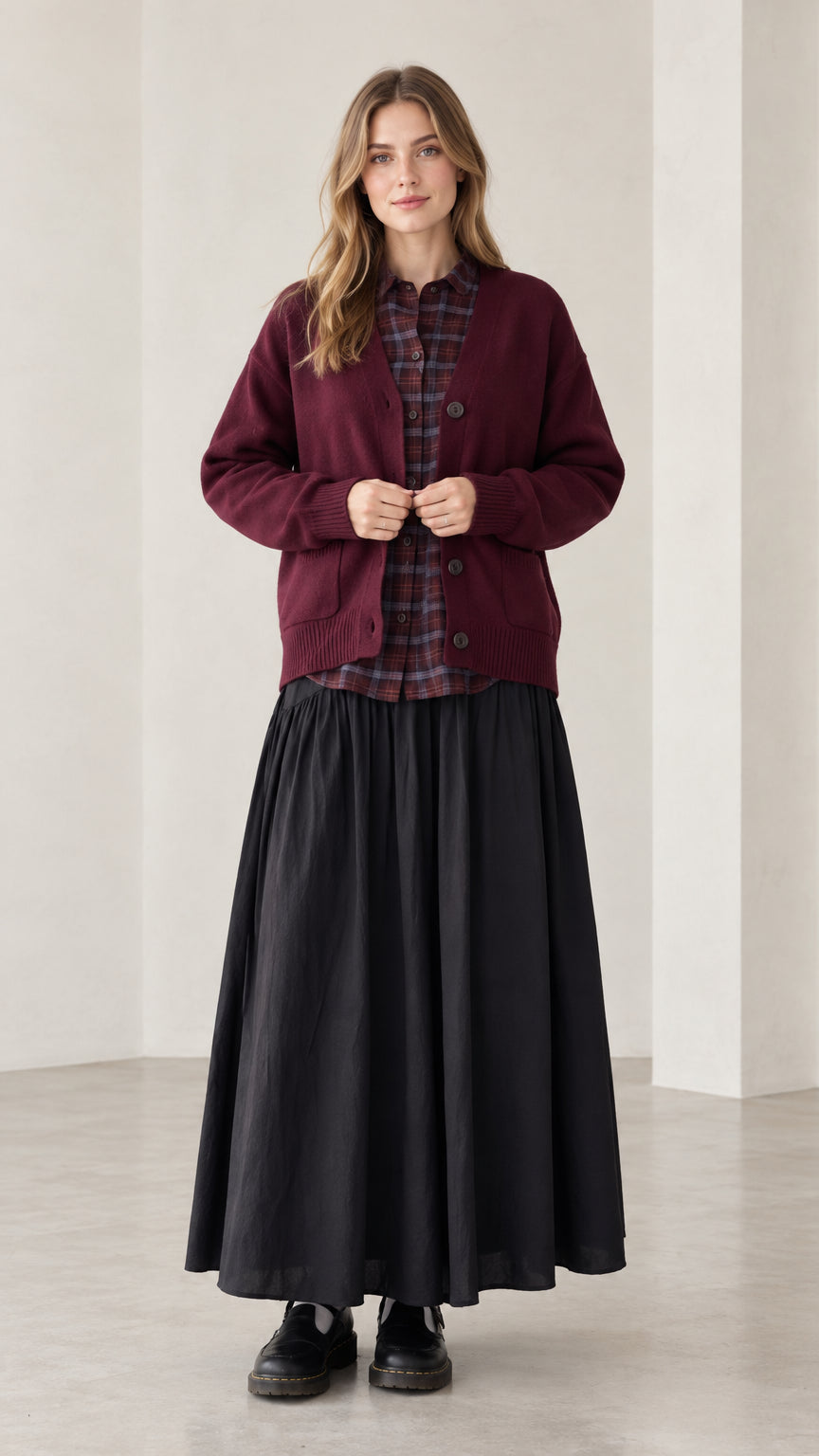 Front view of woman wearing burgundy V-neck button-front knit cardigan sweater with black maxi skirt