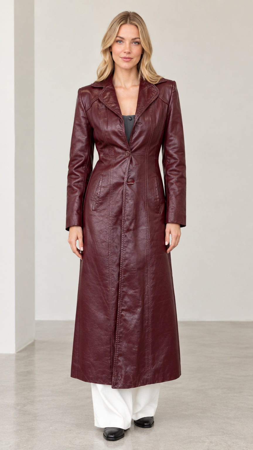Front view of woman wearing burgundy textured faux leather maxi trench coat with wide-leg white pants