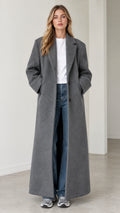 Full front view of model wearing a grey floor-length maxi tailored overcoat over a white tee and jeans