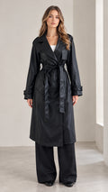 Full front view of a woman modeling the black belted trench coat and wide-leg pants set