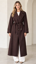 Front full view of woman wearing dark brown double-breasted longline belted trench coat