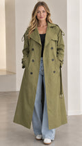 Front full-length view of woman wearing an olive green maxi double-breasted trench coat