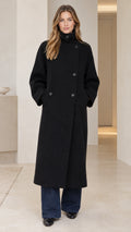 Front view of model wearing black high neck asymmetric longline overcoat with wide leg trousers