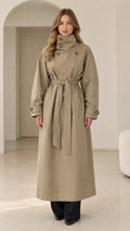 Front full view of woman wearing khaki high neck maxi trench coat with waist tie