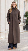 Front view of woman wearing brown high stand collar longline overcoat with wide-leg trousers