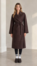 Front full view of woman wearing brown longline belted trench coat