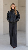 Front view of model wearing the black high-neck zip-up bomber jacket with wide-leg jeans