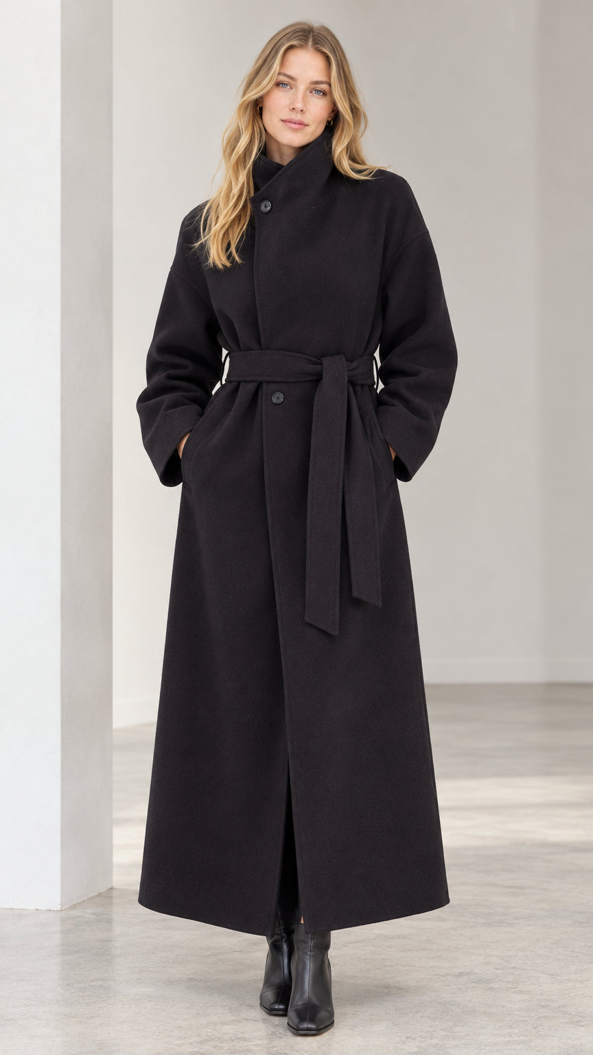 Front view of woman wearing black high neck belted maxi overcoat with black boots