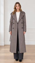 Front full view of woman wearing taupe maxi double-breasted trench coat with tie belt