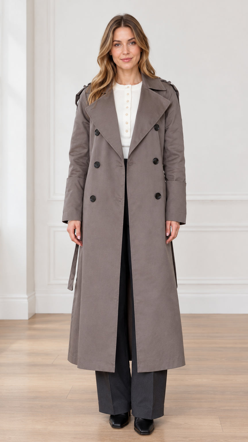 Front full view of woman wearing taupe maxi double-breasted trench coat with tie belt