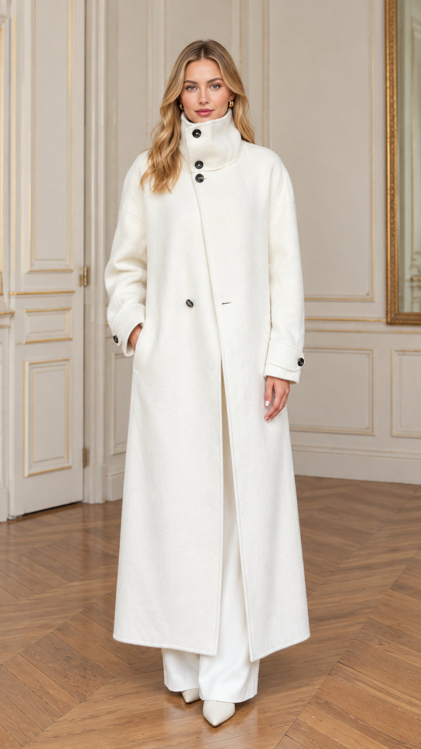 Full front view of a woman wearing an off-white stand collar maxi overcoat with white trousers