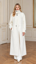 Full front view of a woman wearing an off-white stand collar maxi overcoat with white trousers