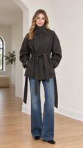 Front view of model wearing charcoal high-neck belted wrap coat paired with flare jeans