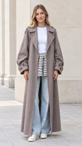 Front full view of woman wearing taupe oversized maxi trench coat with denim jeans