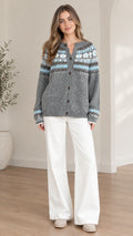 Front view of model wearing a grey Fair Isle button-front cardigan sweater with white wide-leg trousers