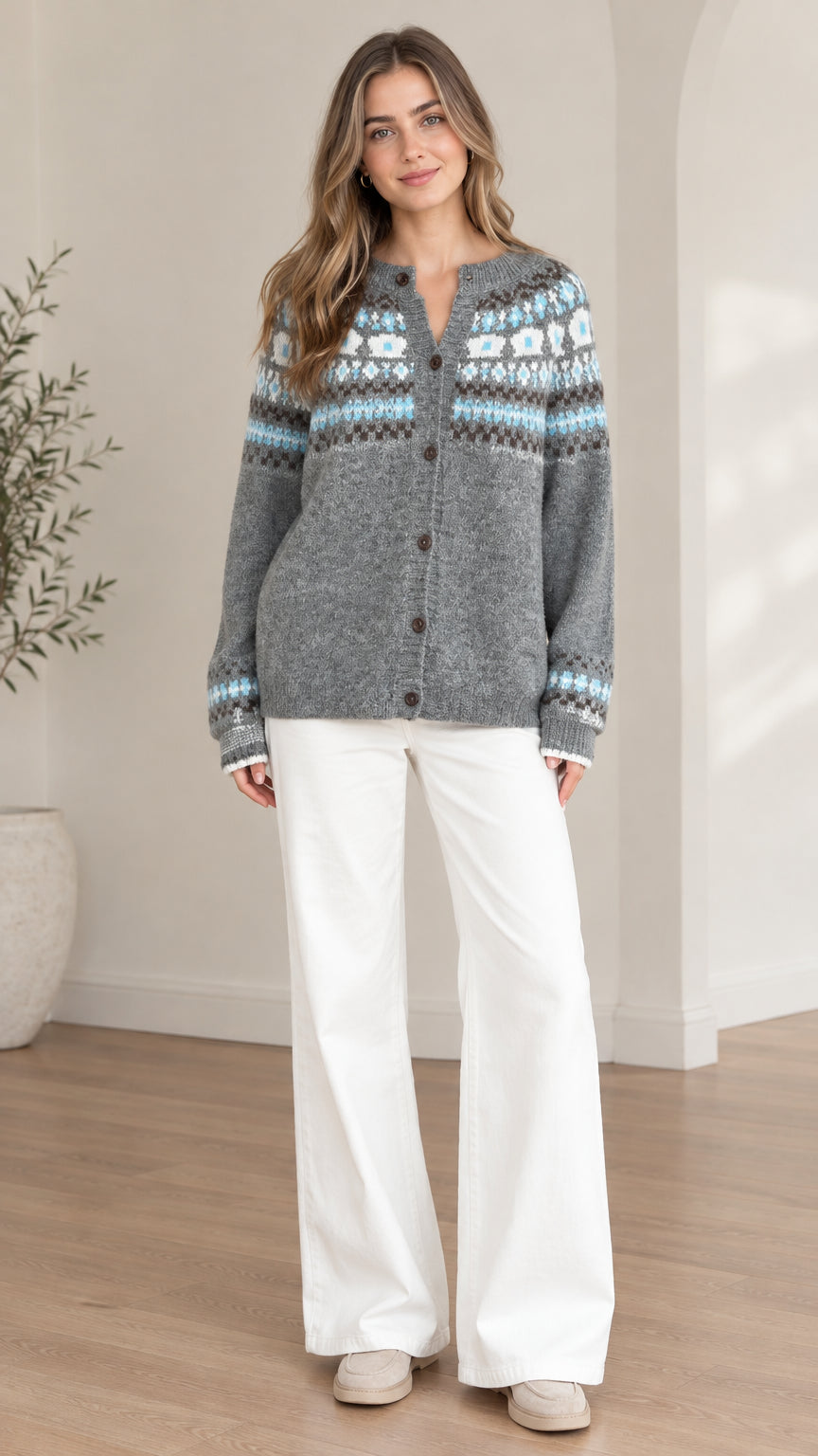 Front view of model wearing a grey Fair Isle button-front cardigan sweater with white wide-leg trousers