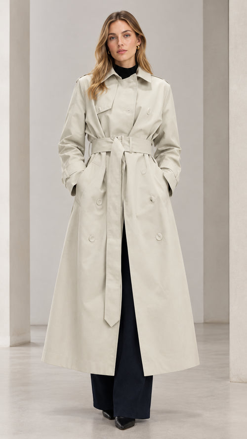 Front view of woman wearing Light Beige double-breasted maxi trench coat with tied belt