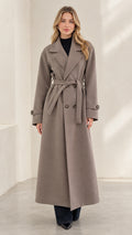 Front full-length view of woman wearing taupe double-breasted long overcoat with tie belt