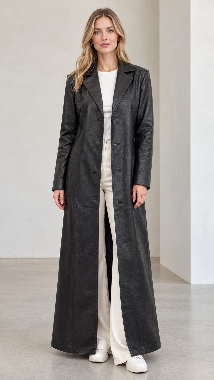 Front full view of woman wearing full-length black faux leather trench coat