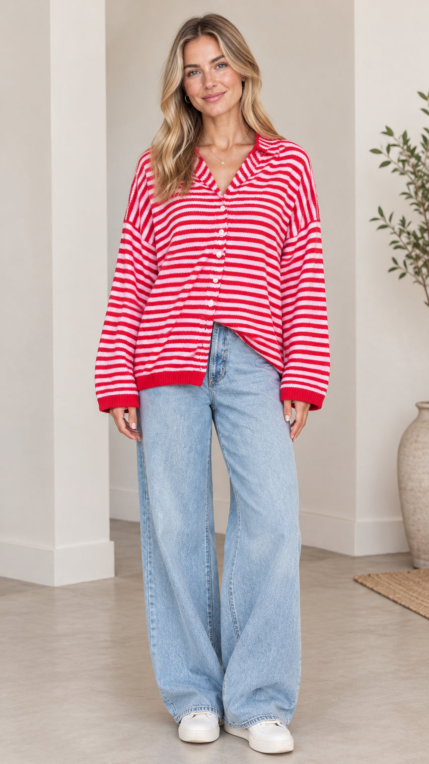 Front full-length view of woman wearing red and white striped collared cardigan sweater with wide-leg jeans