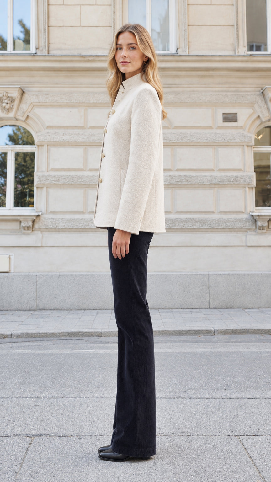 Side profile view of a woman wearing a cream tailored jacquard stand collar jacket