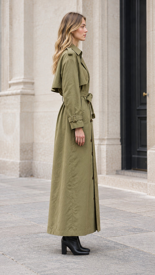 Side profile view of woman modeling maxi olive green trench coat with shoulder storm flap